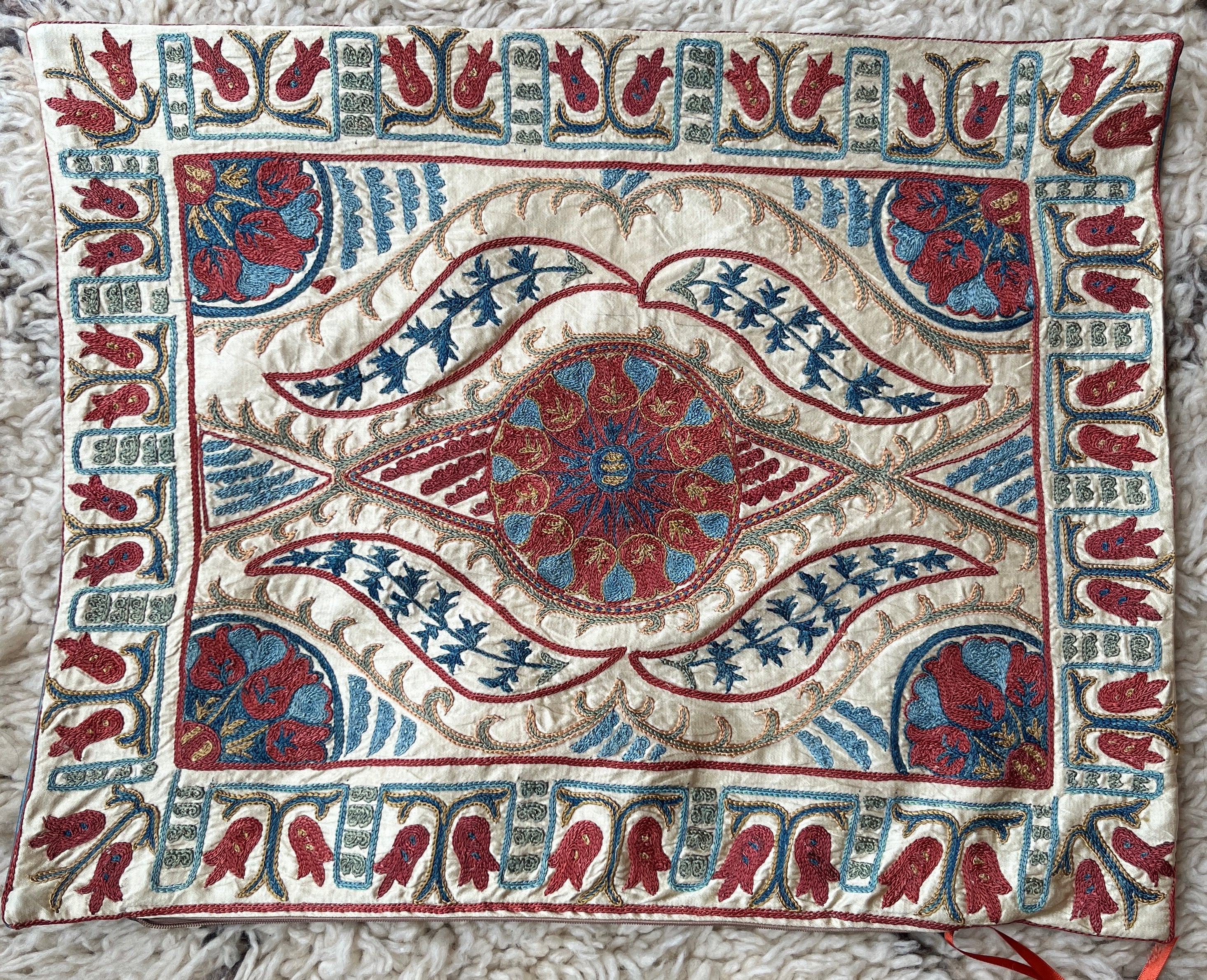 Rectangular Ottoman-style Suzani cushion with a central rosette, flowing saz leaves, and a tulip border.